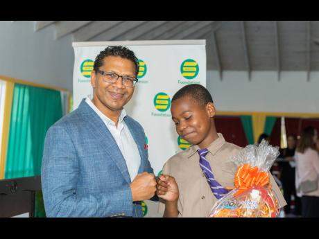 Chief Executive Officer of the Seprod Group, Richard Pandohie, congratulates Tevin Parkes at the Seprod Foundation Annual PEP Scholarship Awards Ceremony, which was held in Kingston on November 21. Tevin was one of 96 students awarded a scholarship under t
