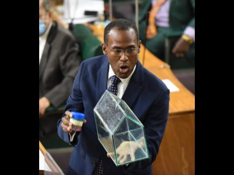 Dr Nigel Clarke, minister of finance and the public service, holds a replica glass house while making his closing arguments in the 2021-22 Budget Debate. Jamaica's Budget transparency rating has improved.