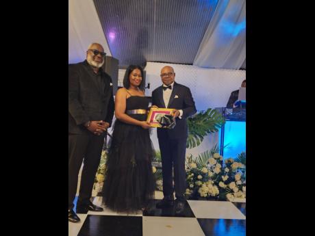 Minister of Tourism Edmund Bartlett (right) accepts a gift from Jamaica to Chike Nwobu and his wife Jackie of Munaluchi Coterie during their gala at the Half Moon on Wednesday evening.
