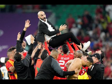 Morocco’s head coach Walid Regragui is thrown in the air by players after the World Cup quarterfinal match between Morocco and Portugal at Al Thumama Stadium in Doha, Qatar on  Saturday, December 10, 2022. 
