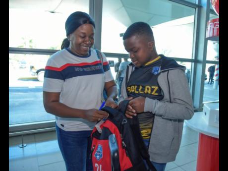 Nathan Stephens (right) gets some help to tag his bag from his mother Ann-Marie Stephens at the Norman Manley International Airport yesterday, shortly before he left the island with other members of the Ballaz International youth squads to compete at the S