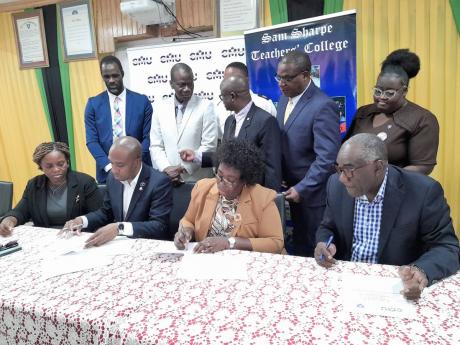 Caribbean Maritime University (CMU) president, Professor Andrew Spencer (second left, seated), and principal of Sam Sharpe Teachers’ College (SSTC), Dr Lorna Gow-Morrison (second right, seated), sign a memorandum of understanding (MOU) for SSTC to formal