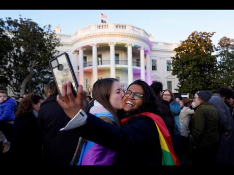Aparna Shrivastava (right) takes a photo as her partner Shelby Teeter gives her a kiss, after President Joe Biden signed the Respect for Marriage Act, yesterday, on the South Lawn of the White House in Washington.