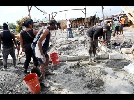 Vendors work to rebuild their stalls which were destroyed  at the Coronation Market after an 
early-morning fire on Sunday, December 11.