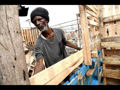 Ephriam White helps his cousin Elaine Gray, a vendor to rebuild her stalls at the Coronation Market  on Tuesday in time for the Christmas sales.