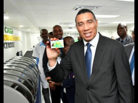 Prime Minister Andrew Holness shows off his National Identification System (NIDS) card during the NIDS Technical Pilot launch ceremony at the Jamaica Post Central Sorting Office on Tuesday..