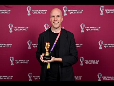 Grant Wahl smiles as he holds a World Cup replica trophy during an award ceremony in Doha, Qatar on November 29, 2022. 