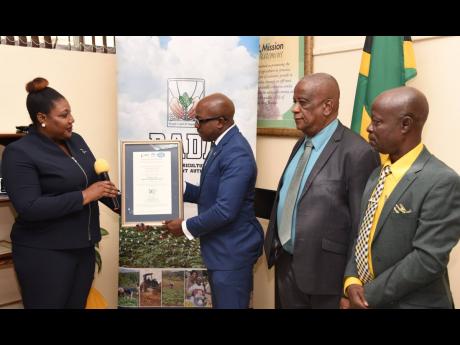 Minister of Agriculture and Fisheries Pearnel Charles Jr. (second left) receives the Rural Agricultural Development Authority’s (RADA) ISO 9001:2015 certificate during a hand over ceremony at RADA’s head office in Kingston on December 13. Making the pr