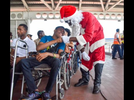 Mark Davidson (left), an actor from the National Pantomime, playing Santa, greets Oneil Christie at the annual Christmas treat for youngsters with disabilities at the Half-Way Tree Transport Centre in St Andrew on Thursday.
