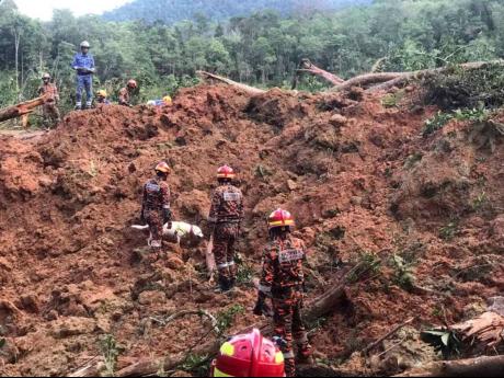 In this photo released by Korporat JBPM, rescuers work at a campsite following a landslide, in Batang Kali, Selangor state, on the outskirts of Kuala Lumpur, Malaysia today. A landslide today at a tourist campground in Malaysia left more than a dozen of pe