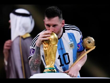 Argentina’s Lionel Messi kisses the World Cup trophy as he holds the the Golden Ball award for best player of the tournament after the thrilling final against France at the Lusail Stadium in Qatar Sunday. 