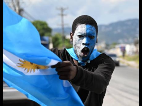 Argentina fan Ackeem Smith celebrates his team’s World Cup win over France on Molynes Road on Sunday.