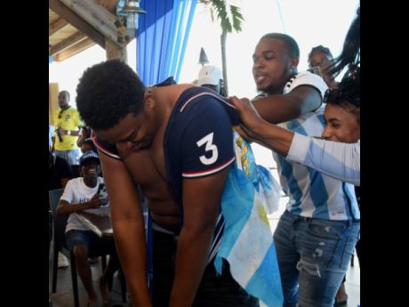 Argentina supporters playfully rip off the jersey of France fan Joshua Vassell at Pier One in Montego Bay, St James, on Sunday. Argentina defeated France 4-2 on penalties to win the World Cup after an enthralling 3-3 tie in extra time.