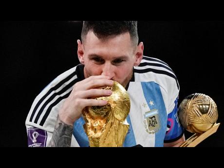 Argentina’s Lionel Messi kisses the World Cup trophy with the golden ball trophy in his hand after the World Cup final against France at the Lusail Stadium in Lusail, Qatar, on Sunday.