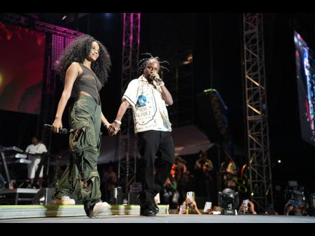 Dancehall artiste Popcaan (right), Miss World 2019 Toni-Ann Singh walk hand-in-hand on stage at Burna Boy Live at the National Stadium in Kingston.