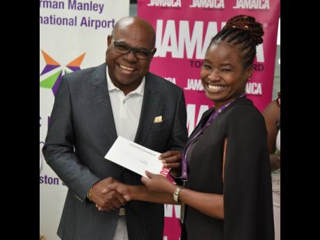 Minister of Tourism Edmund Bartlett presents Kaydian Dawes-Wynter from the Jamaica Tourist Board with the Chairman’s Award during the Jamaica Tourist Board Appreciation Activity for the Norman Manley International Airport Airport team.