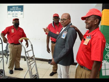 Minister of Tourism Edmund Bartlett (second right) chats with members of the Red Cap Porters at the Norman Manley International Airport (NMIA) during the Jamaica Tourist Board’s appreciation activity for the NMIA team on Tuesday.