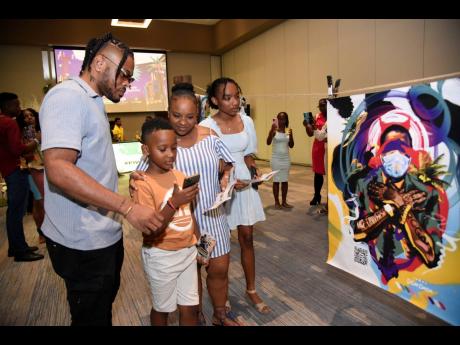 From left: Bonito ‘Don Dada’ Thompson assists Damion Jr, Jhenessa and Jheanell Arnold with scanning his artwork for the ultimate experience.