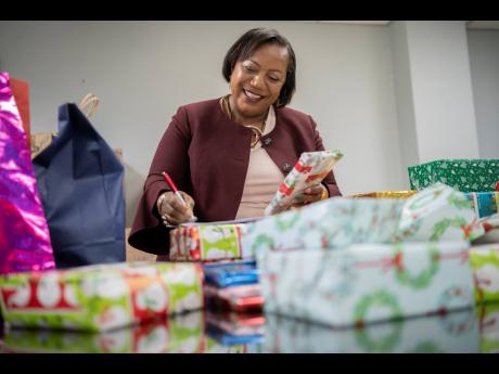 Rosalee Gage-Grey checks off Christmas gifts to be delivered to children’s homes across the island.