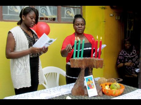 In this file photo, people participate in Kwanza activities at the home of Queen Mother Mariamne Samad (right) in January 2018. Samad has since died.