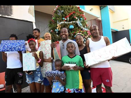 Members of the Balance Family from Parade Gardens in central Kingston show off some of the gifts to be shared at their annual pixie gift-exchange initiative on Hanover Street on Monday.