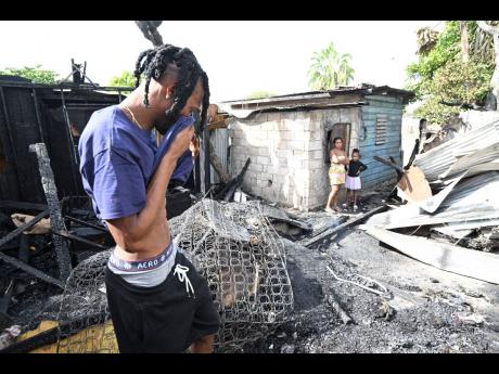 Shadane Francis, a resident of Rae Town in Kingston, wipes the tears as he surveys the charred remains of his home on Monday after a fire destroyed the one-bedroom unit he shared with his teenage nephew.