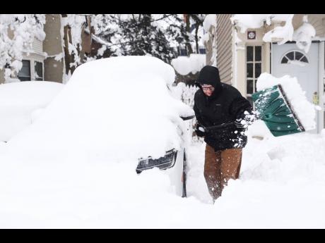 Mike Sweeney tries to clear snow away from his girlfriend’s Volkswagen Tiguan outside their home in Buffalo’s Elmwood Village on Monday, December 26.
