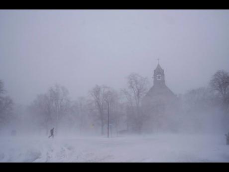 A lone pedestrian makes his way across Colonial Circle as St. John’ Grace Episcopal Church rises above the blowing snow amid blizzard conditions in Buffalo, New York on Saturday, December 24.