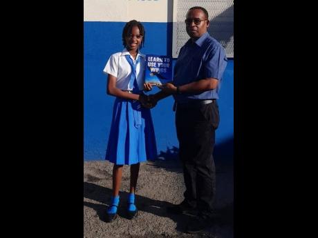 Gianna Hylton presents a copy of her book to her school principal Noel Perkins at St Catherine Preparatory School.