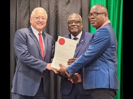 From left: Justice Minister Delroy Chuck and St James Custos Bishop Conrad Pitkin present Robert Barclay with his seal and certificate during a commissioning ceremony for new justices of the peace in St James on Thursday.