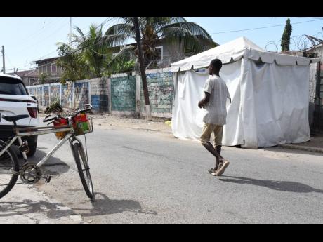 A man walks by a tent used by Jamaica Defence Force personnel at a security checkpoint along Mahoe Drive in St Andrew South Western, where a soldier reportedly shot himself accidentally in the foot early Thursday morning.