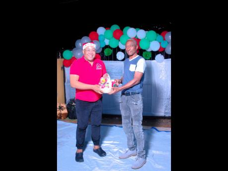 Sheldon Millington, founder of the House of SDM (left), hands over a gift to a resident of New Haven during a Christmas treat put on by the organisation over the holidays.