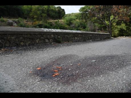 Bloodstains and shattered mark the spot along the Cane River main road in Bull Bay, St Andrew, where three men were shot dead on Saturday night.