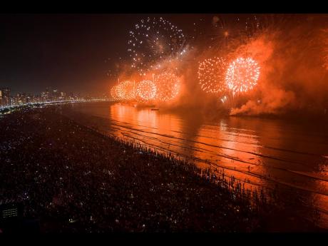 People ring in the New Year as they watch fireworks explode over Santos Bay, in Santos, Brazil, early Sunday morning.