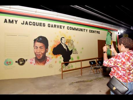 Dr Angela Brown Burke captures an image of the mural bearing the images of Amy Jacques Garvey and her husband, National Hero Marcus Garvey, during the rededication of the Jacques Road Community Centre in Jacques Garvey’s honour last Saturday.