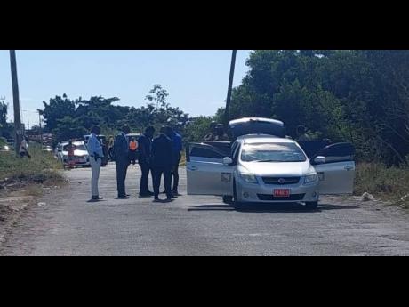 Investigators look at the motor car which was being driven by Javon Ferguson when he was killed in Seaview Gardens, St Andrew, on Wednesday.