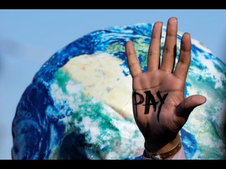 AP 
A hand reads “pay” calling for reparations for loss and damage at the COP27 UN Climate Summit on November 18, 2022, in Sharm el-Sheikh, Egypt.