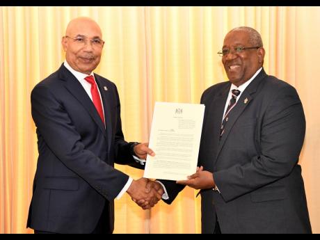 Governor General Sir Patrick Allen (left) presents the proclamation to Professor Dale Webber, principal of The University of The West Indies (UWI), Mona, on Thursday. The UWI is celebrating its 75th anniversary this year.