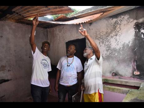 Riley Green (right) from Cherry District, Dover, St Catherine, asks for help to rebuild his house from Michael Tulloch (left) and Enroy Thomas, members of GIVE Foundation, when they visited to present him with a care package recently.  The foundation deliv