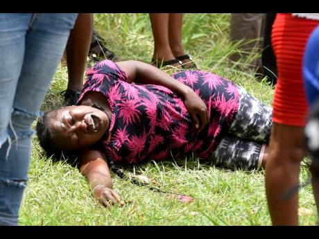 A woman fell to the ground, devastated by the slaughter of the five family members in Cocoa Piece, Clarendon on June 21.