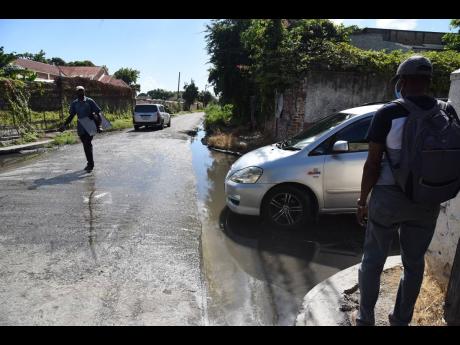 A man walks in the middle of the road to get past murky water settled at the intersection of King Street and Barracks Street in Spanish Town, St Catherine. The area has been a bother for both motorists and pedestrians for years because the drains have been