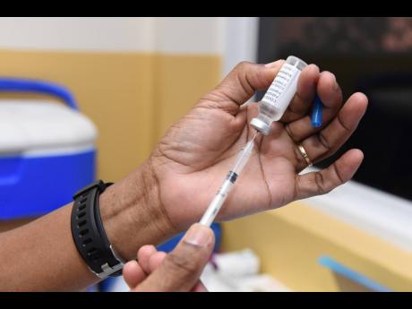 Public Health Nurse Jasmin Thomas fills a syringe with Astra Zenica COVID-19 vaccine at The University Hospital of the West Indies.