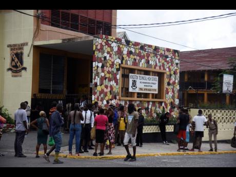 People gather in front of Kingston Technical High School on Hanover Street, where a student who was stabbed to death by another female student in September 2022.