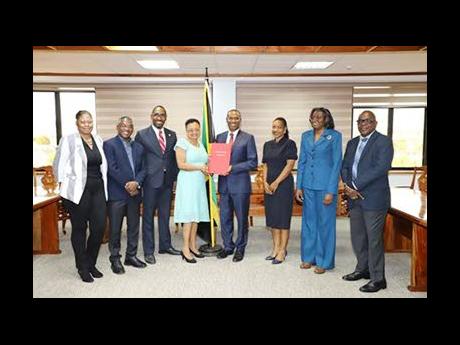 Nigel Clarke (fourth right), minister of finance and the public service, presents the signed MOU to Helene Davis Whyte, president, Jamaica Confederation of Trade Unions. Looking on are (from left)  Maria Thompson Walters, Kavan Gayle, Oniel Grant, Marsha S