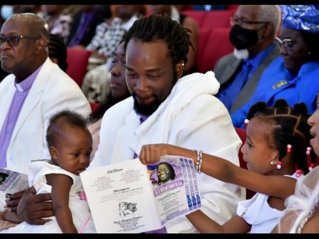 Hailee Mclean shows a picture of her grandmother,  the late Dr Millicent Evadnie McLean, to her father, Harvard Mclean and her sister Helena McLean. Rev Mclean died on December 2, 2022. The memorial service for Evadnie was held at the Portmore Holiness Chr