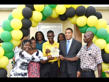 Prime Minister Andrew Holness (second right) hands over the keys to a new three-bedroom house to Delano Tucker and his family ( from left) Denisha, Natrise Tucker and their father Desmond (right). The prime minister was accompanied by Member of Parliament 