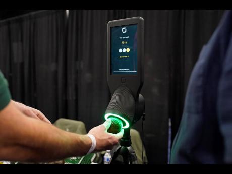 An exhibitor demonstrates the OneThird avocado ripeness checker during CES Unveiled before the start of the CES tech show, in Las Vegas. The device is designed for use by grocery store shoppers to scan an avocado and get information about when it is ready 