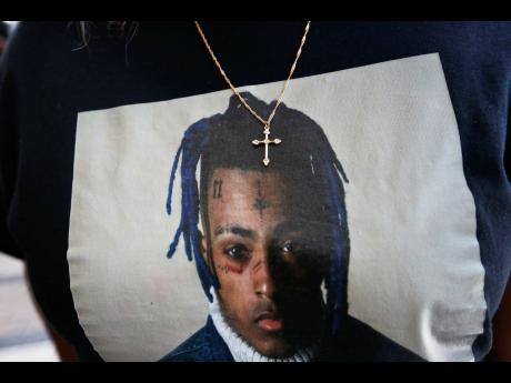 A fan wears a cross around her neck dangling on a t-shirt in remembrance before she enters a memorial for the rapper, XXXTentacion in Sunrise, Florida. More than four years after gunmen killed the emerging rap star XXXTentacion during a robbery outside a S