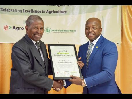 Pearnel Charles Jr (right), minister of agriculture and fisheries, presents agricultural educator Reuben Gray with the Agricultural Legacy Award.