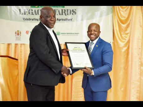 Webster McPherson (left) receives Agricultural Legacy award from Pearnel Charles Jr, minister of agriculture and fisheries.
